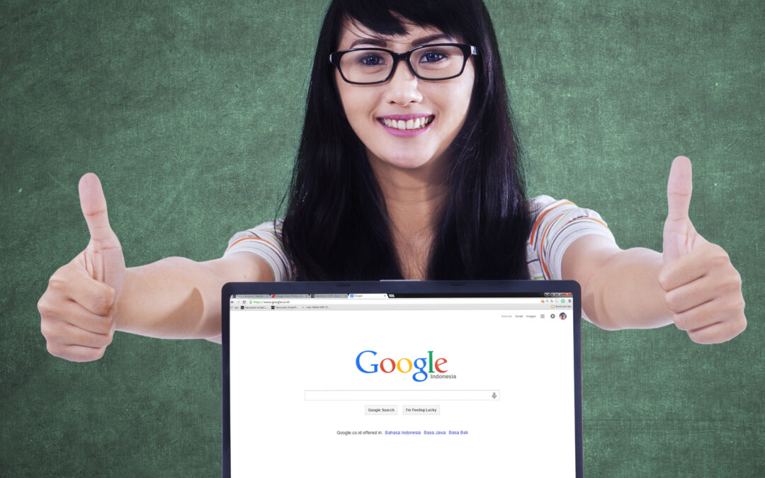 female student with thumbs up behind laptop with Google search